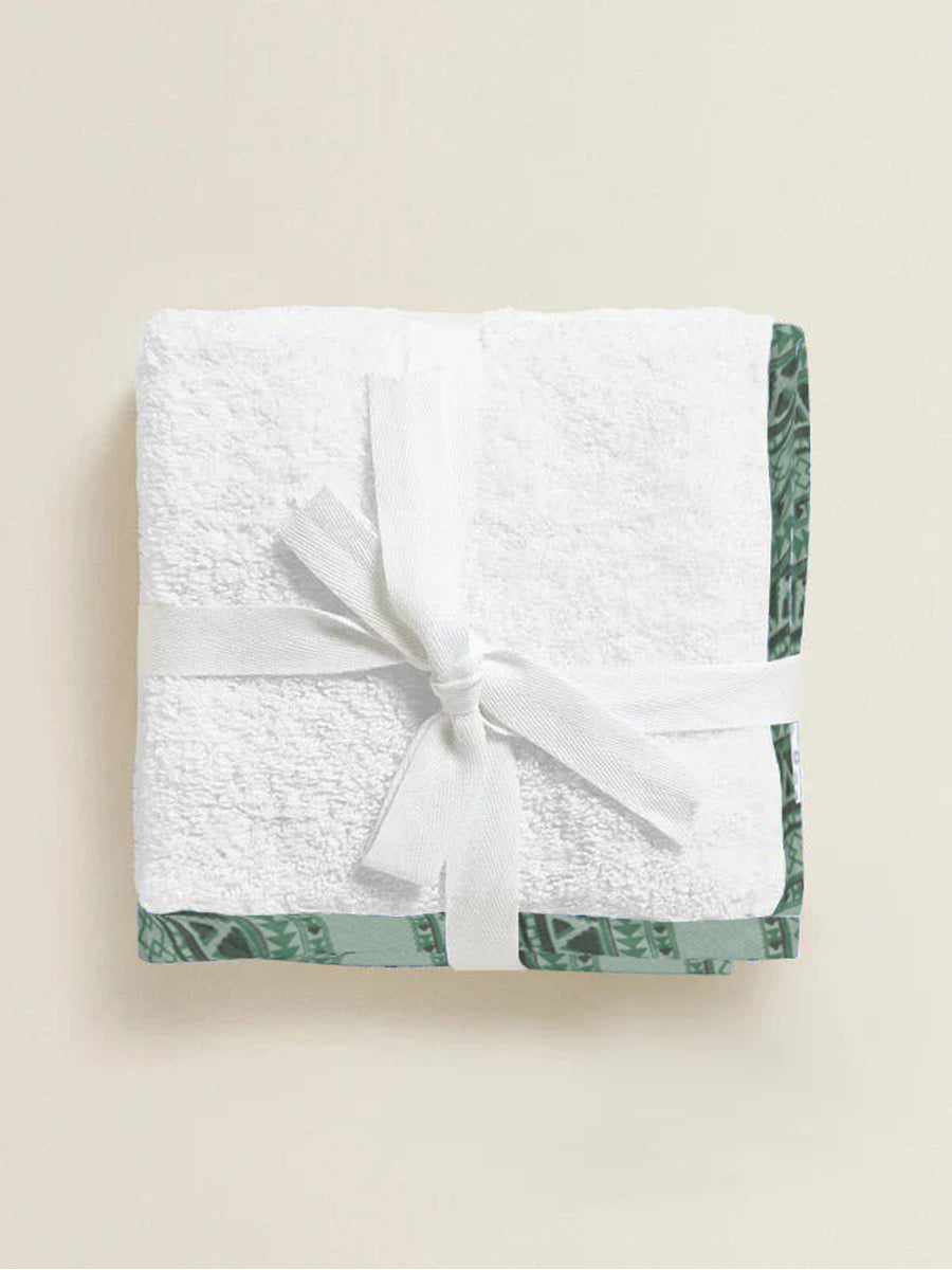 Folded white towel with green trim on a beige background