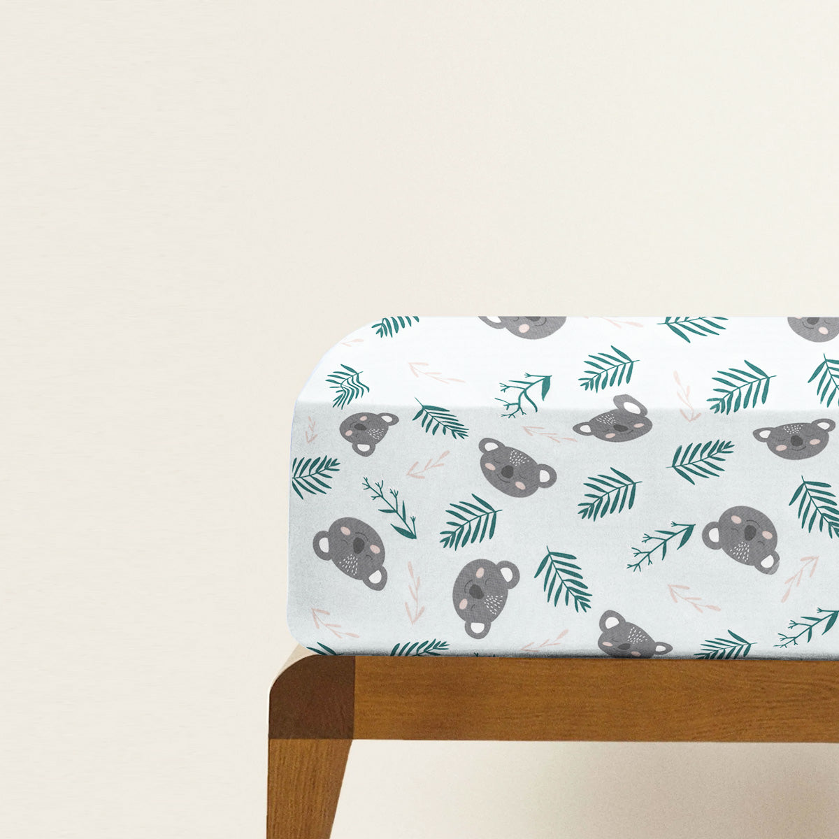 Fitted crib sheet with bear and leaf pattern on a wooden crib