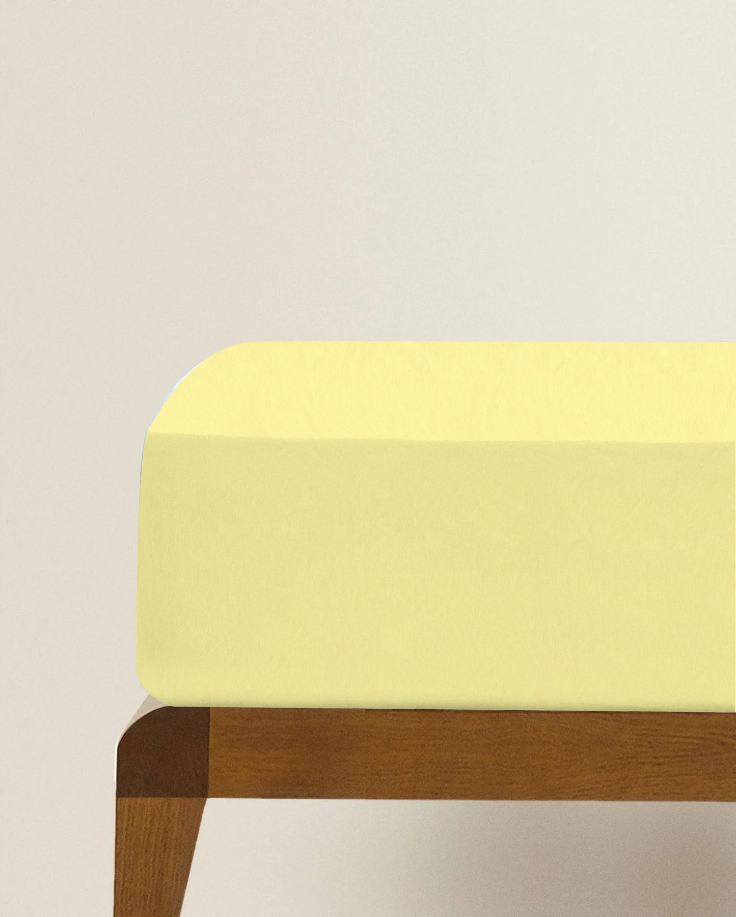 Yellow cushioned stool with wooden legs on a light beige background