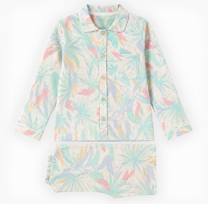 A two-piece children's pajama set featuring a long-sleeve button-front top and matching shorts, both decorated with a tropical palm leaf pattern in pastel mint green, light blue, pink, and yellow on a cream background.