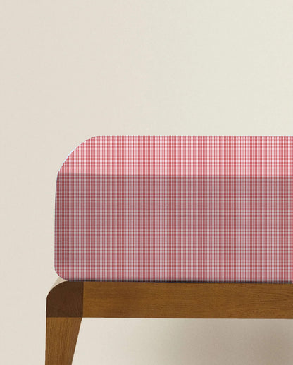 Red and white checkered bench cover on a wooden bench against a beige background