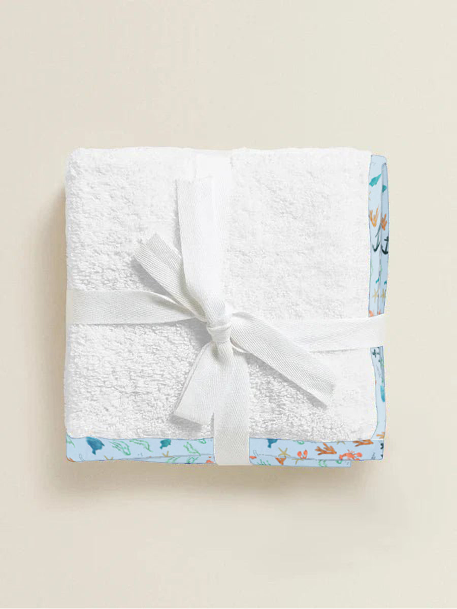 White textured blanket with a sea garden border and white bow on a beige background