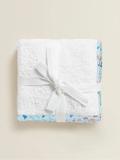 White textured blanket with a sea garden border and white bow on a beige background