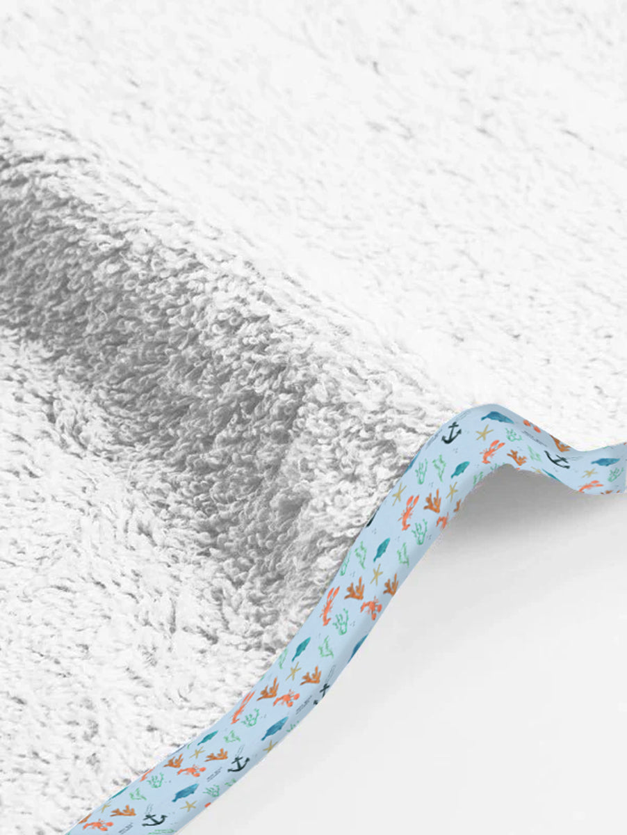 Baby blanket with sea-themed border on a textured white background