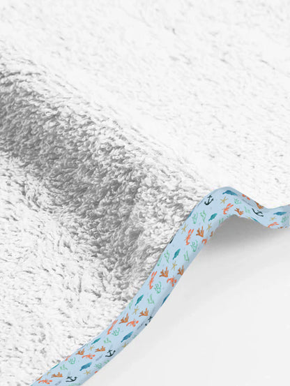 Baby blanket with sea-themed border on a textured white background