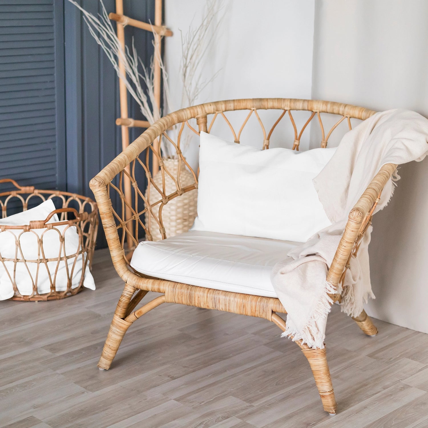 A white organic baby pillow cover with a simple, elegant design, displayed on a rattan baby chair with a neutral-toned textile in the background.