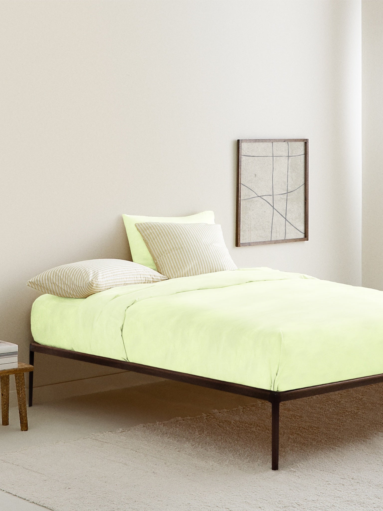 A lime green fitted bed sheet on a bed with a wooden headboard, the sheet is designed for children's bedding.